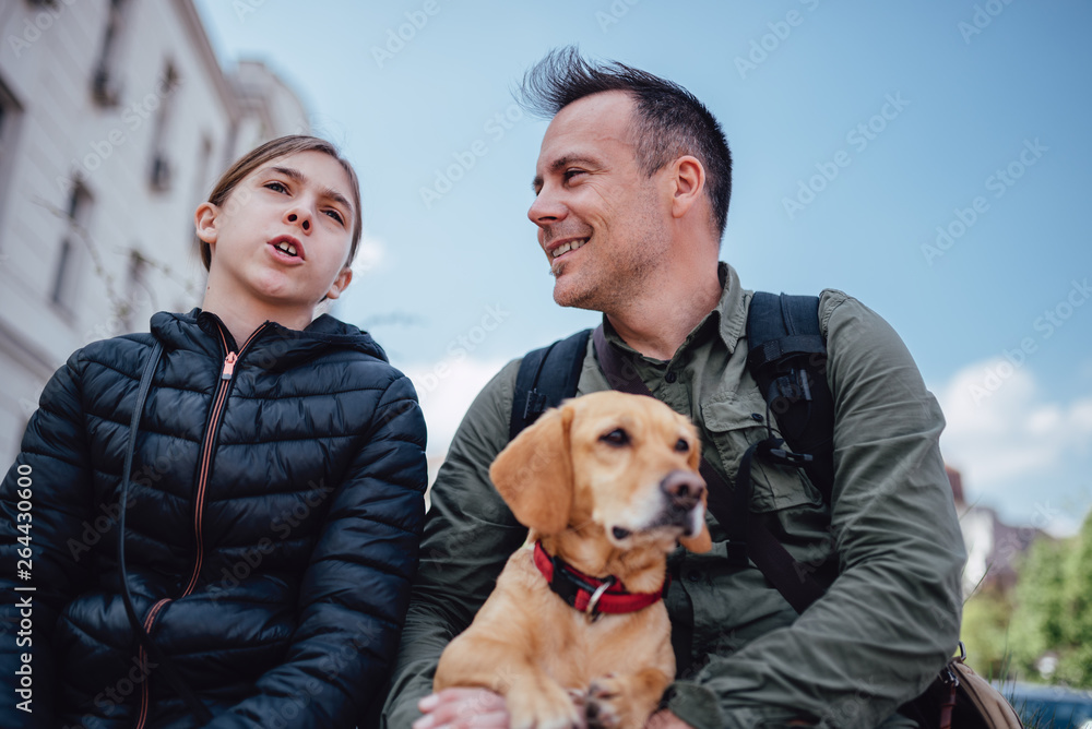 Father and daughter resting outdoors with their dog