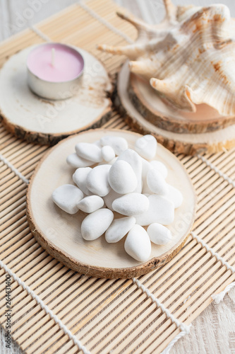 Background of seashell with white stones and candle on wooden mat. Travel summer holiday concept.