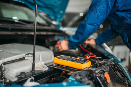 Car electrician checks the battery level