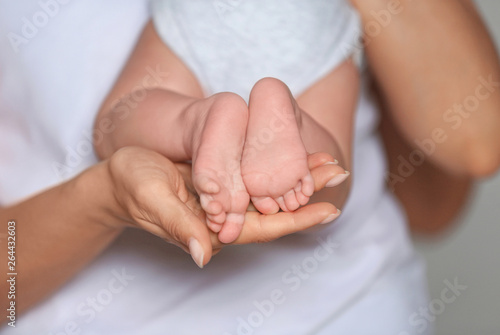Mother holding feet of her cute little baby in hands, closeup