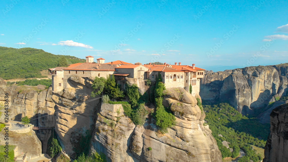 AERIAL: High stone formations surround the idyllic secluded village in Greece.