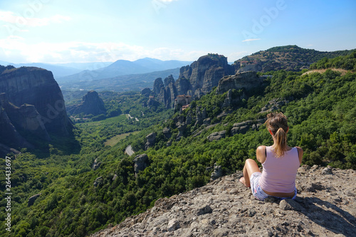CLOSE UP: Woman sitting on top of a cliff and observing the picturesque nature.
