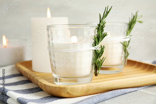 Wooden tray with burning candles on table
