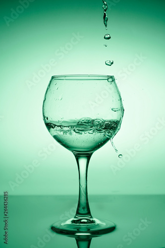 Wine glass with flowing water  white wine  on a background of green gradient