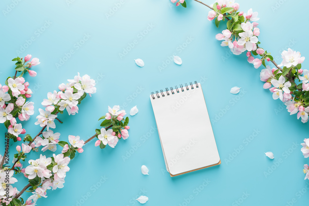 Blooming spring sakura on a blue background with notepad space for a greeting message. The concept of spring and mother's day. Beautiful delicate pink cherry flowers in springtime Blooming spring sakura on a blue background with notepad space for a greeting message. The concept of spring and mother's day. Beautiful delicate pink cherry flowers in springtime