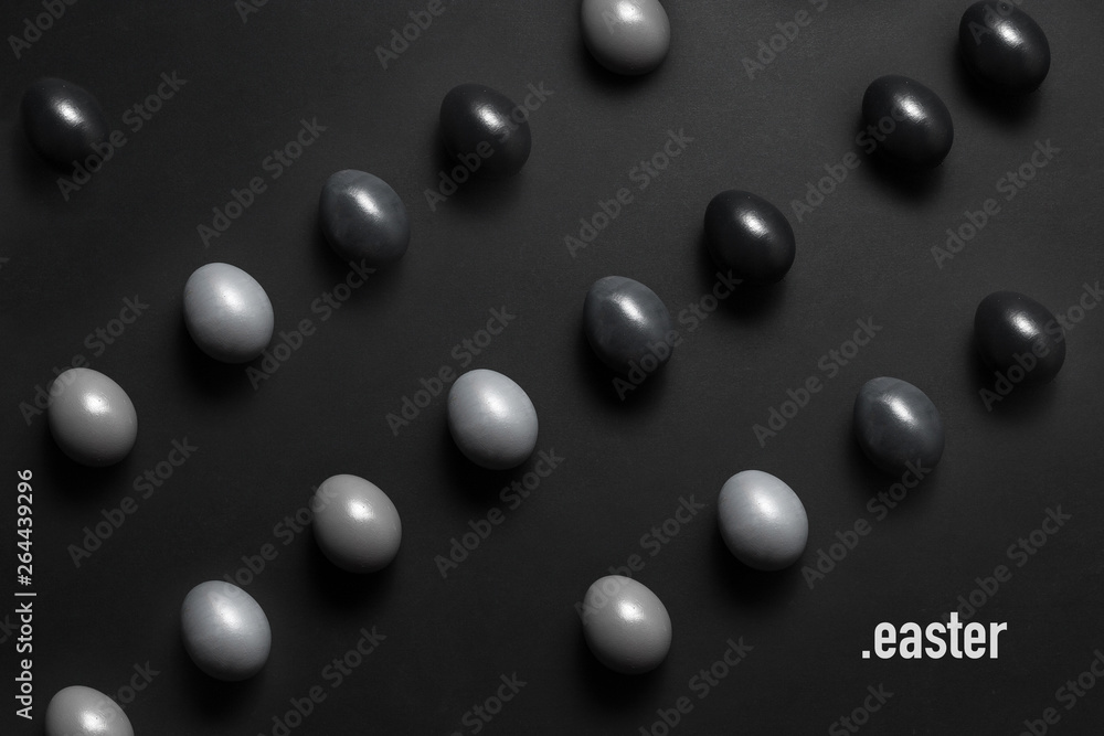 Monochrome gradient Easter eggs lie in a row on a black background, top view with text