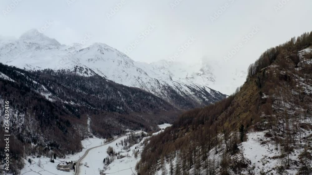 Aerial: Houses in Beautiful Valley Among Snowy Mountains with Pine Forests in South Tyrol, Italy