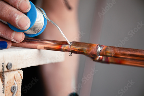 Closeup professional master plumber holding flux paste for soldering and brazing seams of copper pipe gas burner. Concept installation and repair of an apartment building pipeline, leakage photo
