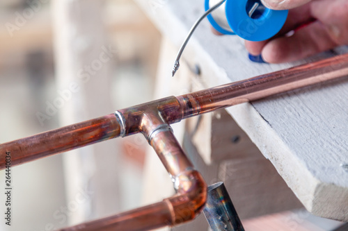 Closeup professional master plumber holding flux paste for soldering and brazing seams of copper pipe gas burner. Concept installation and repair of an apartment building pipeline, leakage