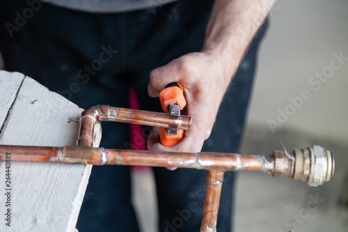 Close-up professional plumber worker plumber cuts pipe and holds it with pliers. Concept installation, replacement plumbing, solder flux paste, pipeline repair, pipe leakage