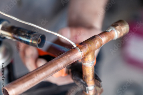 Closeup professional master plumber holding flux paste for soldering and brazing seams of copper pipe gas burner. Concept installation and repair of an apartment building pipeline, leakage