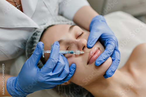Closeup portrait of young woman during cosmetology therapy  injecting in beauty salon. Botox  making lips  modern procedures  lifting  rejuvenation  healthcare  beauty