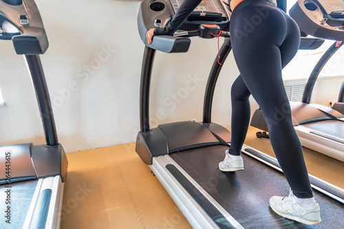 Close up young fit woman on modern treadmill in gym. Lower part view