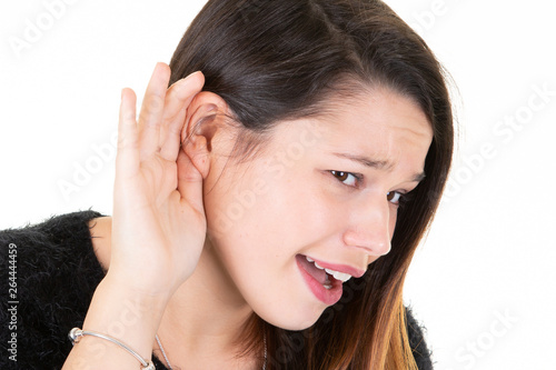 Beautiful young woman puts hand to the ear to hear better listening something over white background