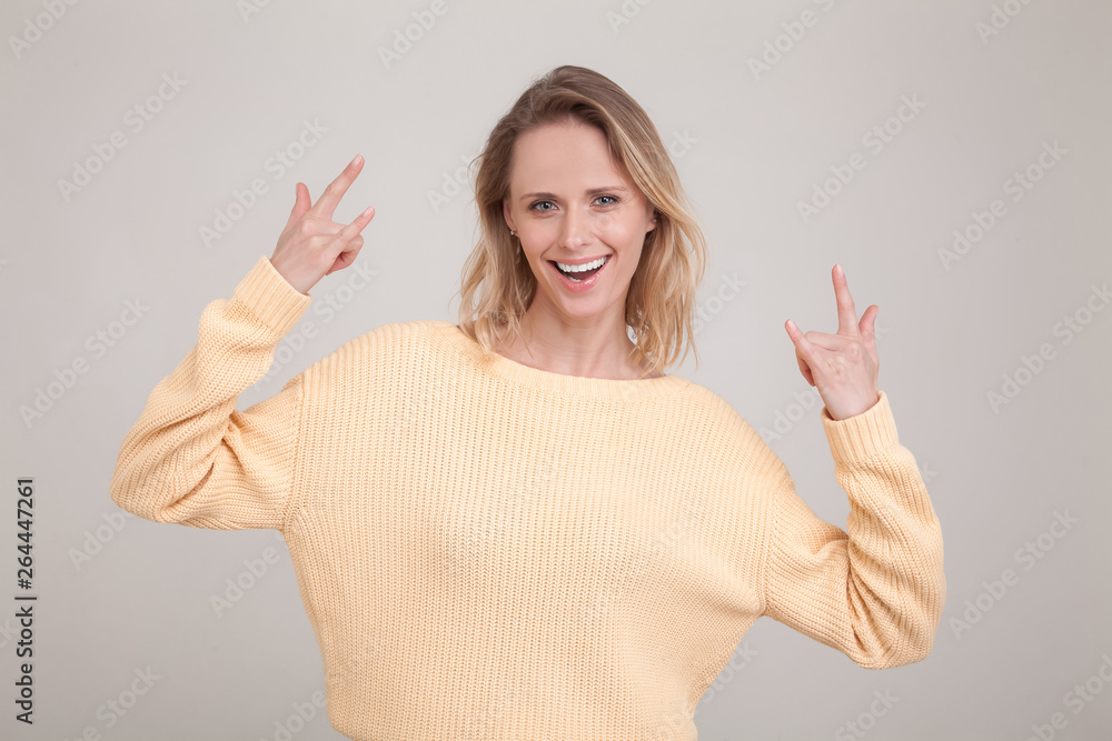 waist-up portrait of happy blonde woman with satisfied carefree attitude, showing rock n roll gestures, smiling broadly, cheering and celebrating b-day of friend waist-up portrait of happy blonde woman with satisfied carefree attitude, showing rock n roll gestures, smiling broadly, cheering and celebrating b-day of friend