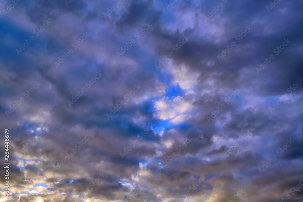Blue sky with gold clouds - dramatic sunset, beautiful natural background. Setting sun illuminates the clouds. Blue sky with gold clouds - dramatic sunset, beautiful natural background. Setting sun illuminates the clouds.