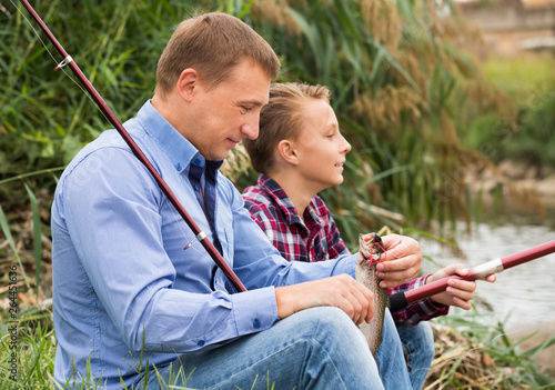 Father and son fishing on river