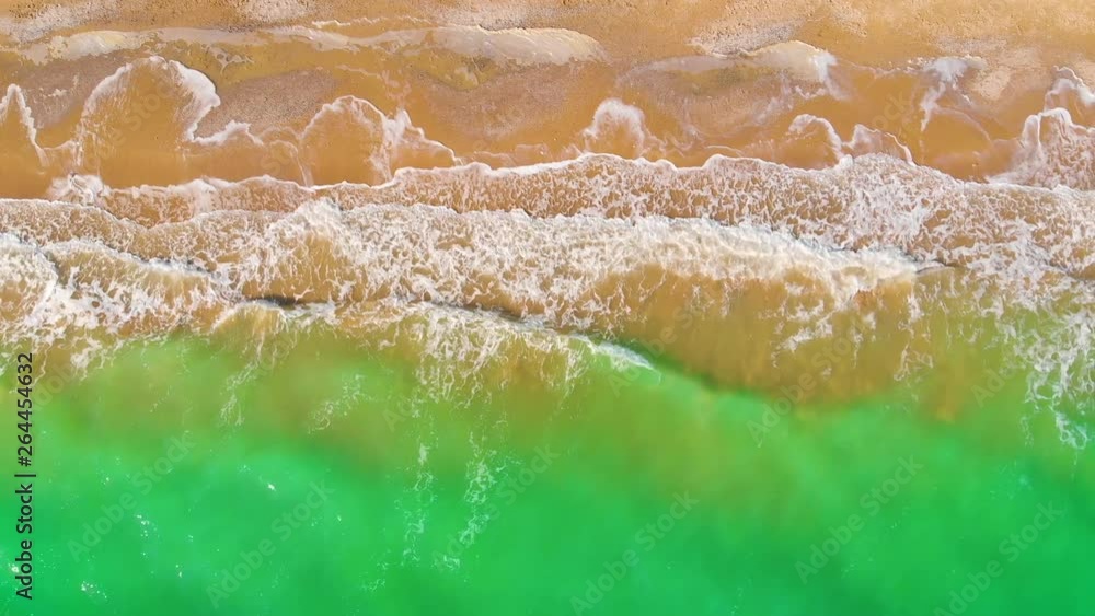 Top view of a superb lonely and deserted beach on the shores of the azure sea. Dawn of nature in 4K. A bird's eye view of ocean waves crashing against an empty beach from above