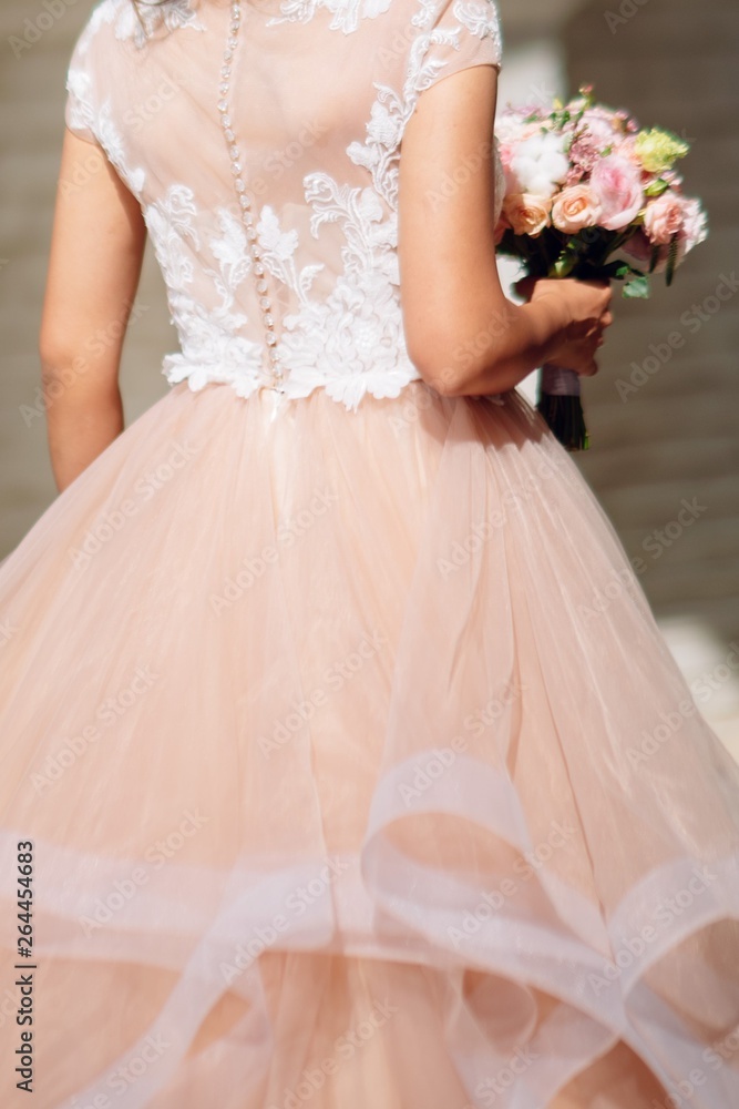 Fototapeta premium Bride in a wedding dress holding a wedding bouquet in her hands close-up