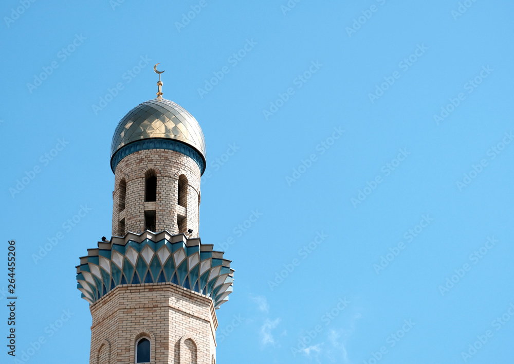 The Golden minaret of the mosque. Muslim symbol on blue sky background with white . Crescent. Islam concept. Religious holiday.