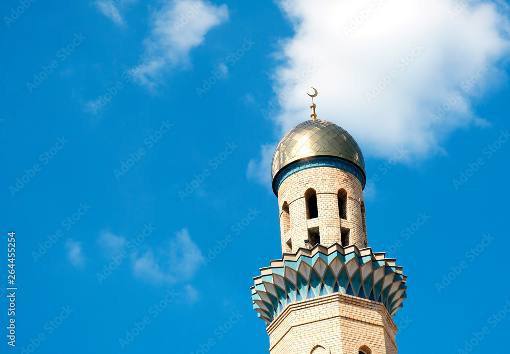 The Golden minaret of the mosque. Muslim symbol on blue sky background with white . Crescent. Islam concept. Religious holiday. The Golden minaret of the mosque. Muslim symbol on blue sky background with white . Crescent. Islam concept. Religious holiday.