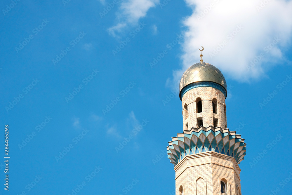 The Golden minaret of the mosque. Muslim symbol on blue sky background with white . Crescent. Islam concept. Religious holiday.