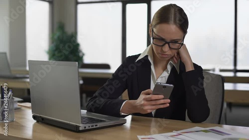 Woman checking social media on phone, distracted from work, productivity concept photo