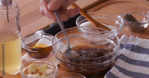 Steak making, preparing marinade, pouring apple vinegar into mixture, mixing using spoon, close-up