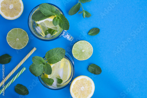 Cold lemonade with lemon and mint  in the glasses on the blue background.Top view.Copy space. © Liudmyla