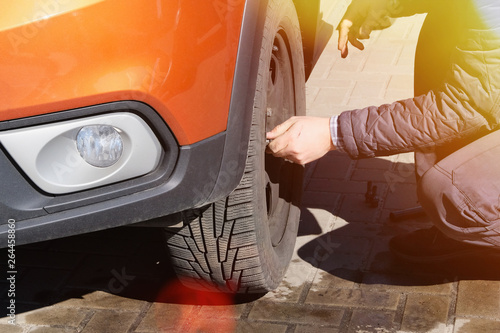 Wheel balancing or repair and change car tire. Automobile maintenance concept. Damaged tyre in orange car. Sunlight.