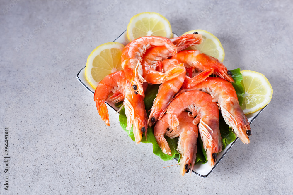plate of boiled shrimps with lemon, on a light gray table, top view plate of boiled shrimps with lemon, on a light gray table, top view