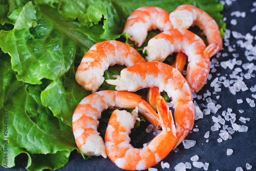 boiled peeled shrimps on lettuce leaves with salt on a gray background, close-up boiled peeled shrimps on lettuce leaves with salt on a gray background, close-up