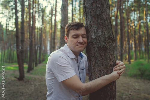 Man hugging tree in the forest. Smiling young male nature lover relax on summer day hug a tree enjoy in beautiful day	