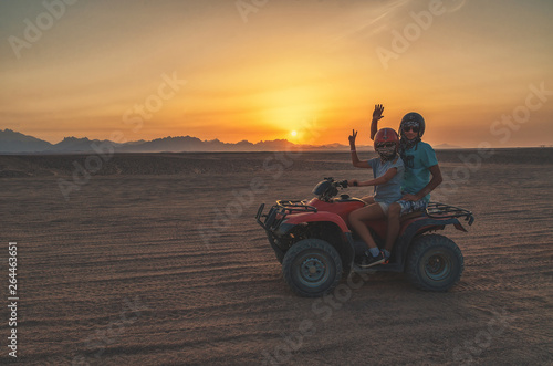 Family travels at sunset in the desert on an ATV