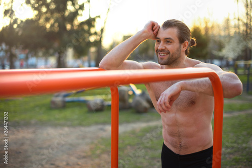 male athlete, torso with muscles, outdoors training, smiling, horizontal bar