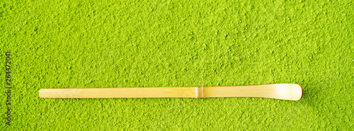 Top view of bamboo Chashaku spoon on powdered Green Matcha tea background with copy space. Long wide banner with copy space. photo