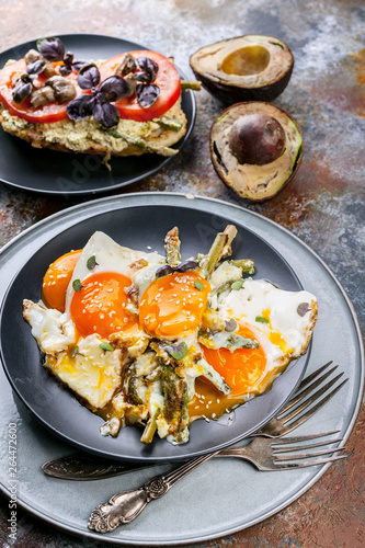 Fried eggs with asparagus  sandwich with pesto  tomatoes and mushrooms  ripe avocado. Tasty breakfast.