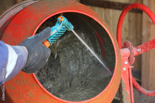 Obraz na płótnie Worker washes red concrete mixer with a stream of water w salonie