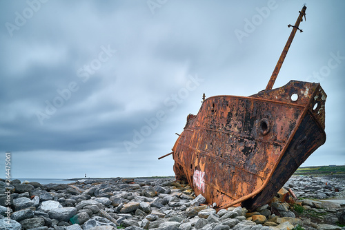 rusty boat tilts on rocks photo