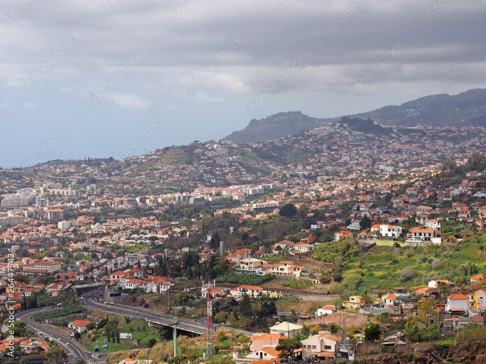 a view of funchal from above showing the city and hills with ocean and blue sky in the distance