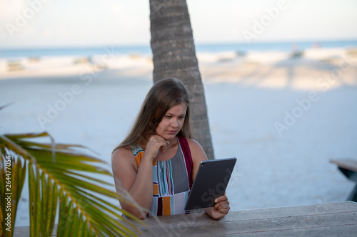 young woman with tablet on the beach