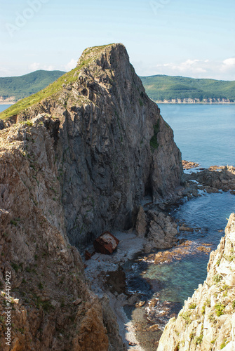 An old shipwrecked ship stands on the shore at the foot of a rocky cliff. Cape Briner. Primorsky Krai. Russia. photo