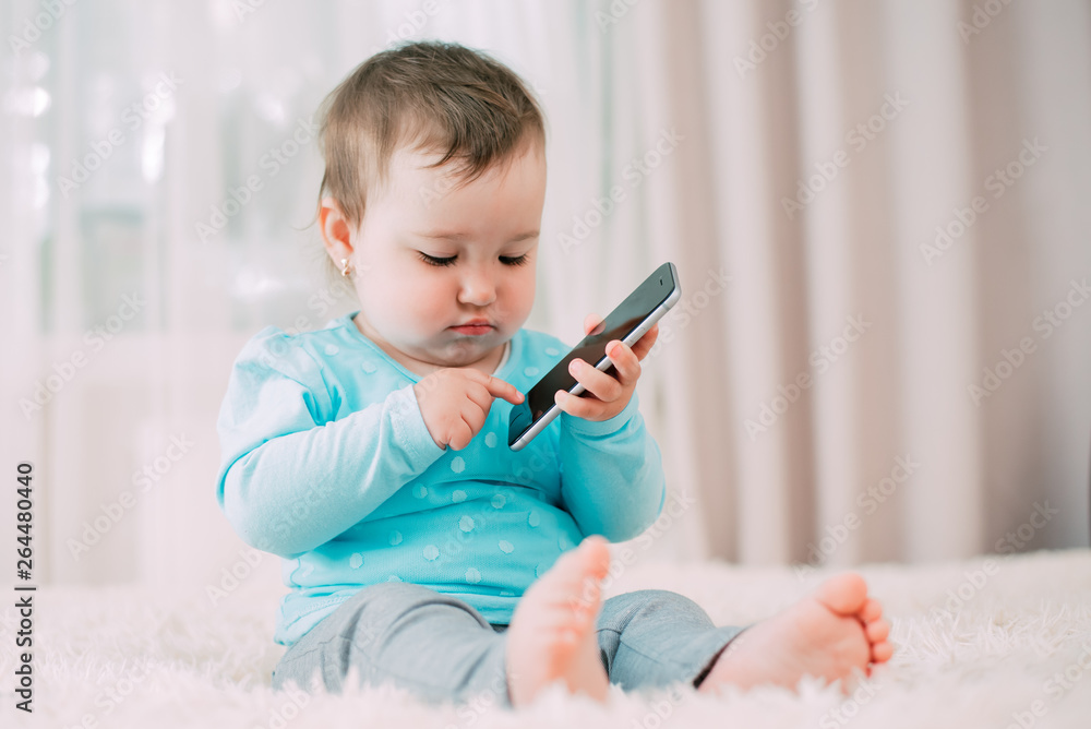 a little girl with a smartphone phone in her hands sits and presses a little girl with a smartphone phone in her hands sits and presses