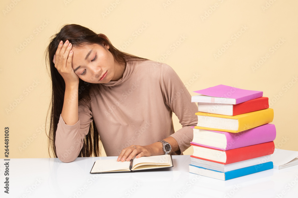 Exhausted Young Asian woman read a book with books on table. Exhausted Young Asian woman read a book with books on table.