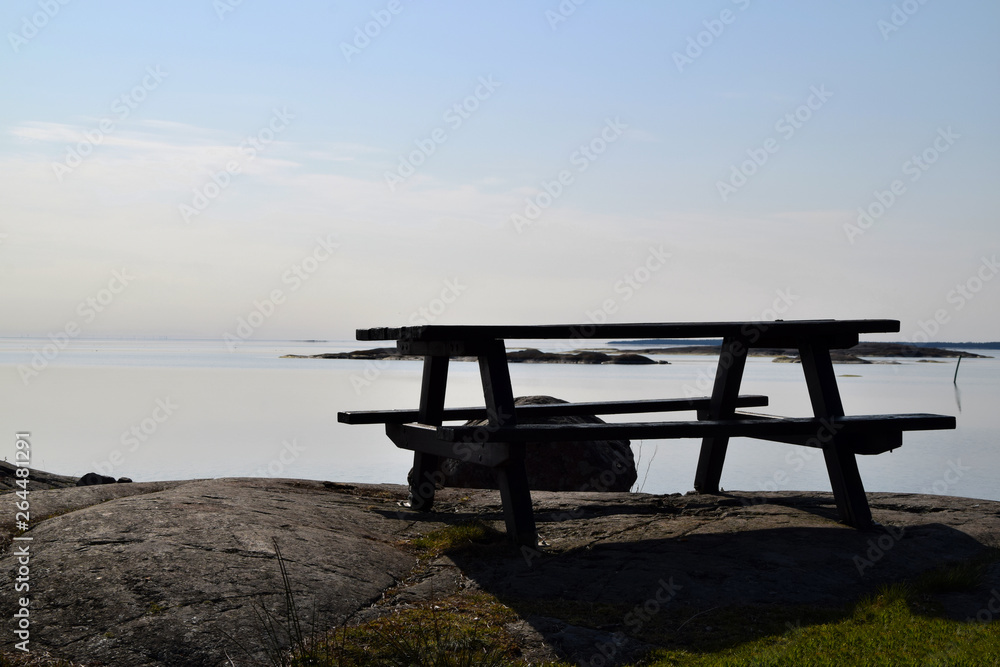Empty picnic table with tranquil water in the background