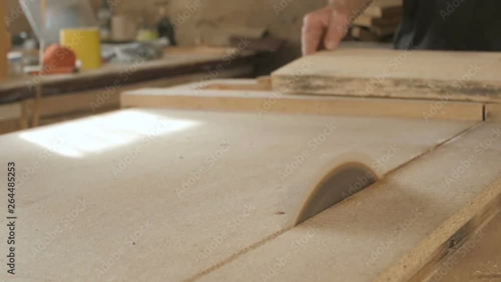 young man cuts a wooden board with a circular saw blade, a workshop with a professional tool for woodworking, a concept of construction working process of manufacturing parts for construction young man cuts a wooden board with a circular saw blade, a workshop with a professional tool for woodworking, a concept of construction working process of manufacturing parts for construction