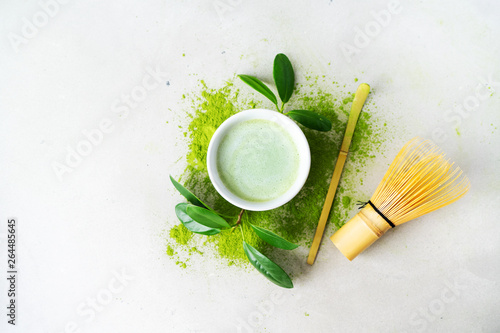 Flat lay of organic green tea Matcha powder with Japanese tools Chasen bamboo whisk, Chashaku spoon and bowl for brewing on light background with copy space.