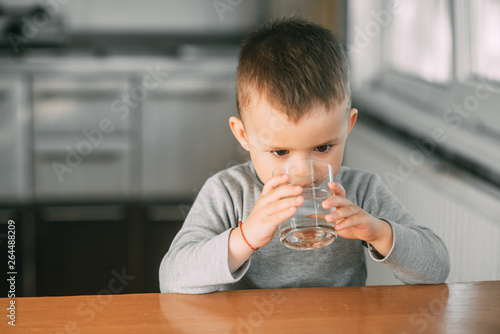Portrait of a boy drinking a glass of water,happy in the kitchen photo