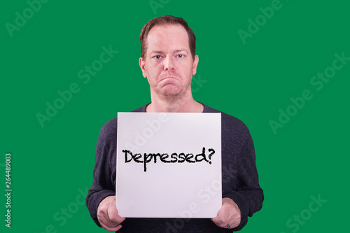 Red haired middle aged freckled adult male frowning holding sign with the word Depressed? captured on green screen background  photo