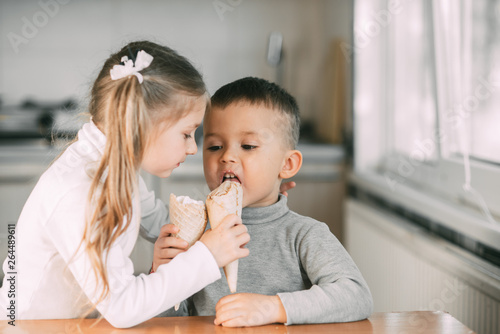 children  boy and girl eating ice cream cone in the kitchen are very fun to share with each other